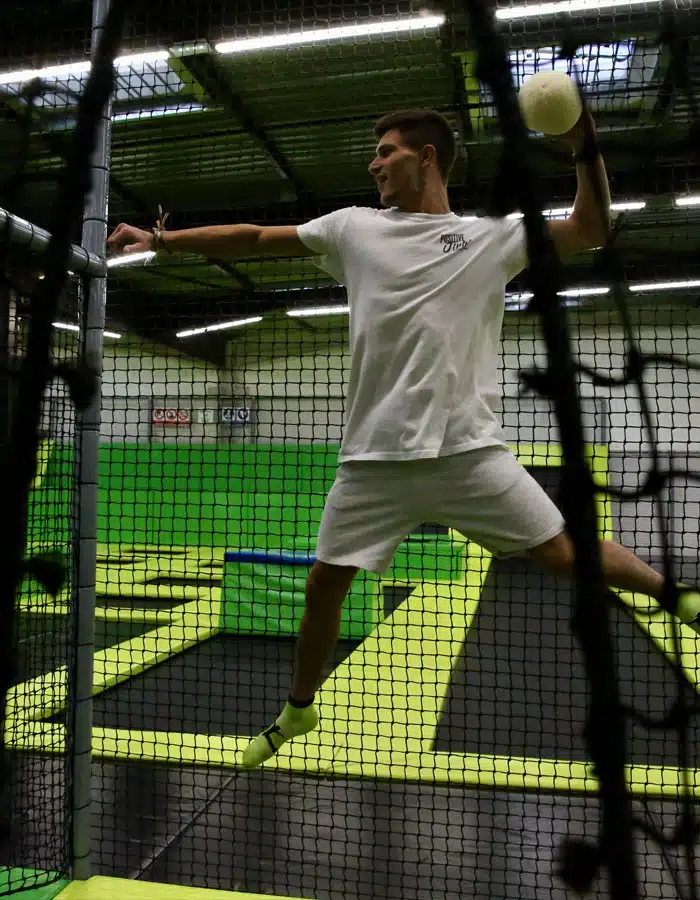 Joueur en plein saut, ballon en main, sur le terrain de dodge ball du Positive Jump