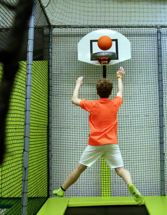 Enfant s'élançant d'un trampoline pour marquer un panier au trampo dunk