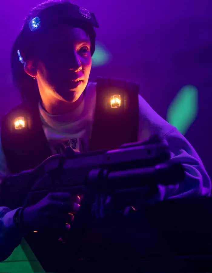 Joueuse équipée d’un gilet lumineux dans l’arène de Laser Game
