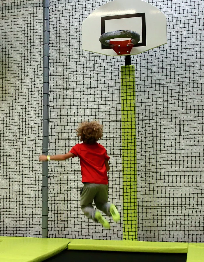 Enfant en plein saut vers le panier haut, dos à l’objectif