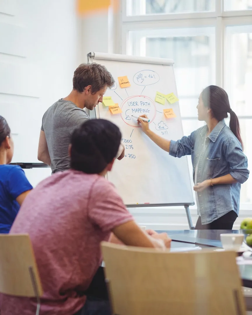 Collègues réunis autour d’un paperboard pendant un séminaire d’entreprise