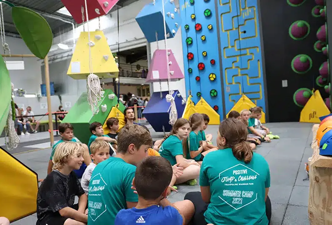 Groupe d’enfants du summer camp assis devant le mur d’escalade du parc