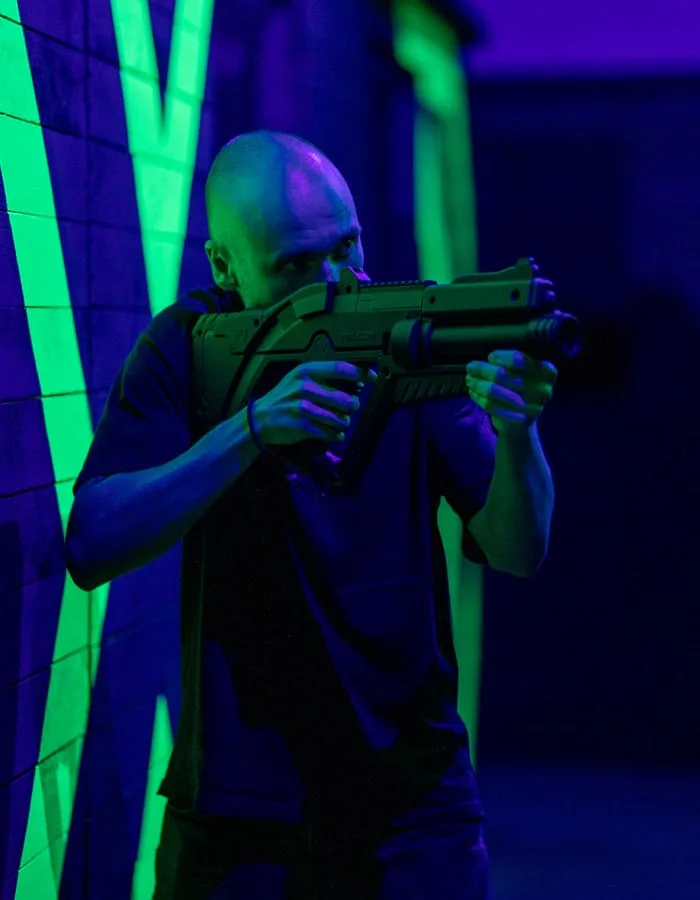 Joueur en joue avec son blaster, sous la lumière noire