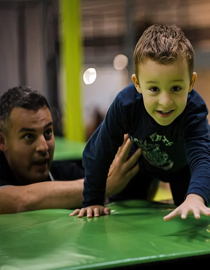 Un père et son fils sur un module vert, à hauteur d’enfant