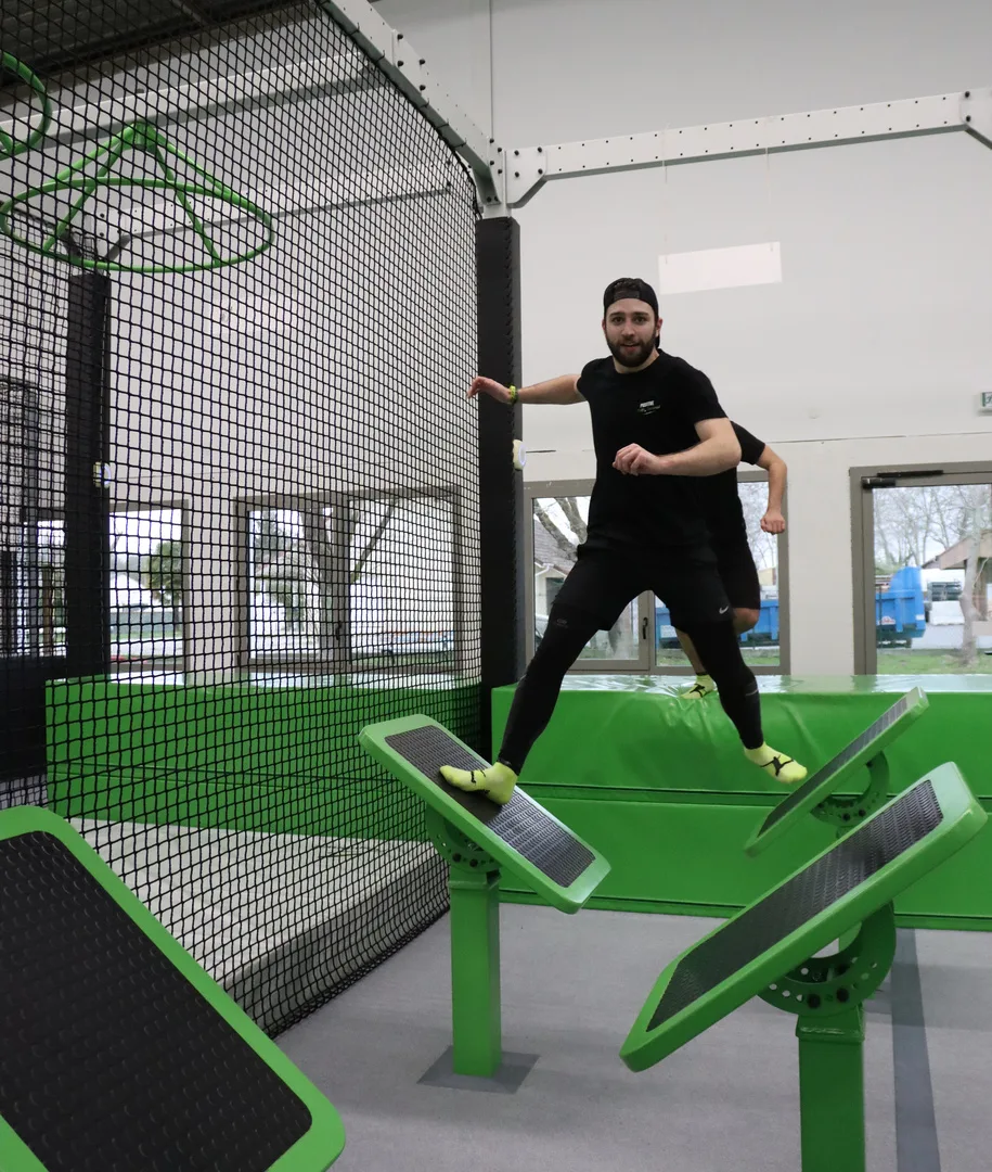 Participant franchissant les plateformes inclinées du parcours Ninja Warrior
